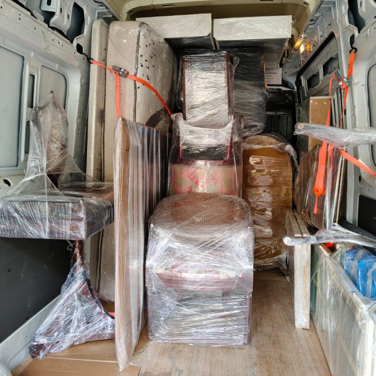 Furgoneta cargada con muebles envueltos en plástico y con cintas de sujeción.
